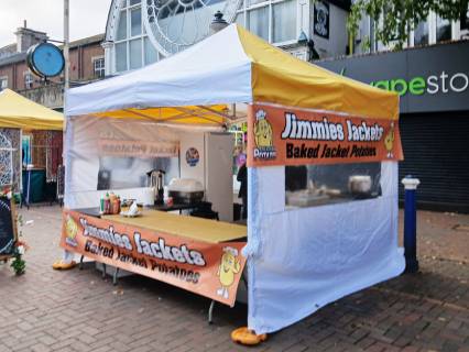 A photo shows a food stall on a high street with a banner saying 'Jimmies Jackets'